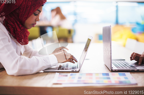 Image of black muslim business woman ,working on laptop computer