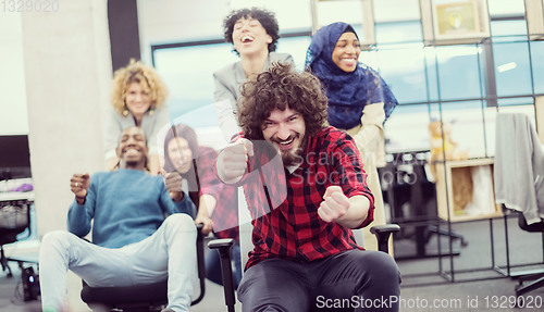 Image of multiethnics business team racing on office chairs