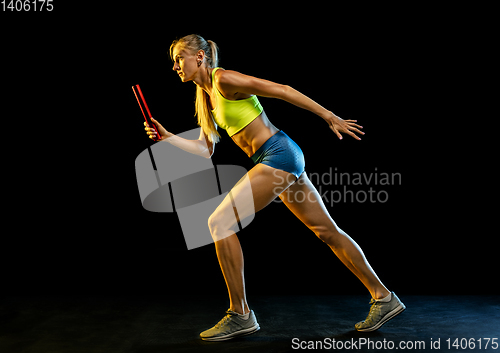 Image of Professional female relay racer training on black studio background in neon light