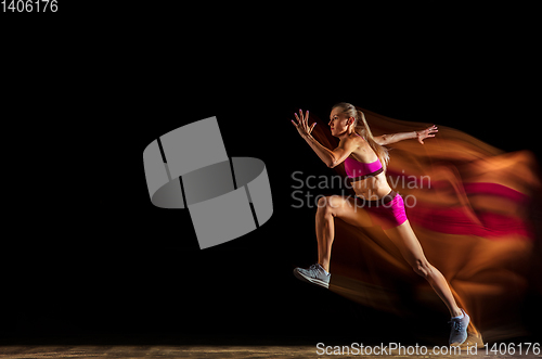 Image of Professional female relay racer training on black studio background in mixed light