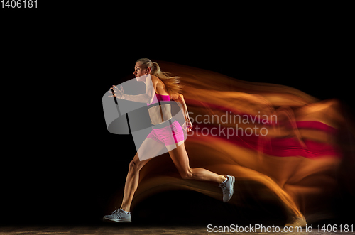 Image of Professional female relay racer training on black studio background in mixed light