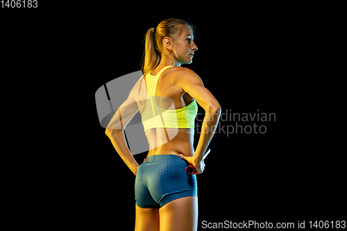 Image of Professional female relay racer training on black studio background in neon light