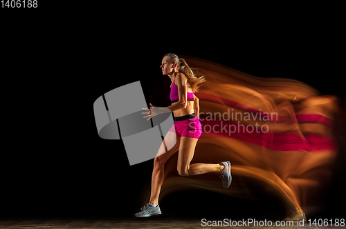 Image of Professional female relay racer training on black studio background in mixed light