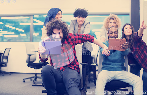 Image of multiethnics business team racing on office chairs