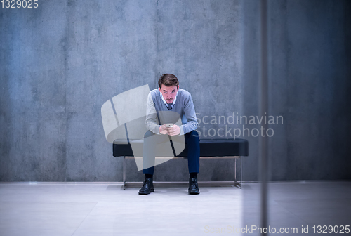 Image of businessman using smart phone while sitting on the bench