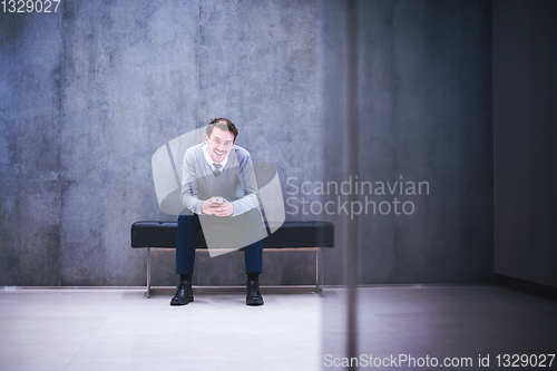 Image of businessman using smart phone while sitting on the bench