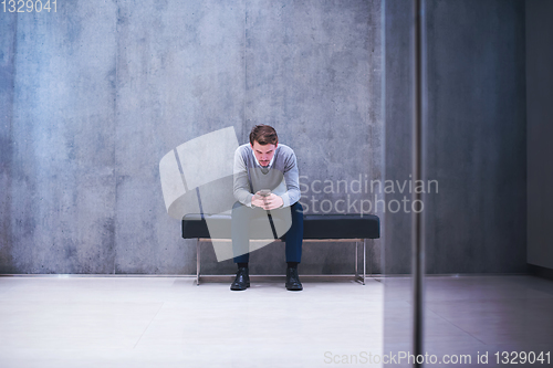 Image of businessman using smart phone while sitting on the bench