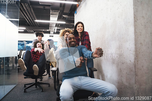 Image of multiethnics business team racing on office chairs