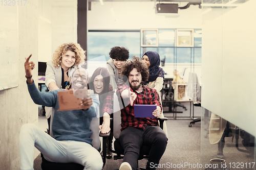 Image of multiethnics business team racing on office chairs