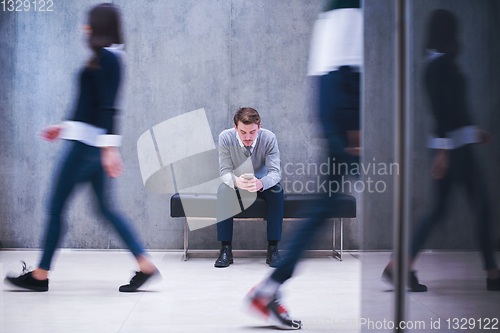 Image of businessman using mobile phone while sitting on the bench