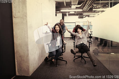 Image of multiethnics business team racing on office chairs