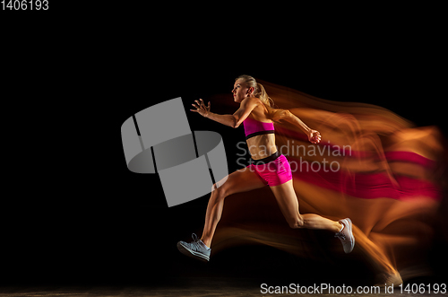 Image of Professional female relay racer training on black studio background in mixed light