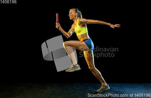 Image of Professional female relay racer training on black studio background in neon light