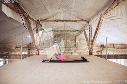 Image of A young athletic woman working out on an abandoned construction site