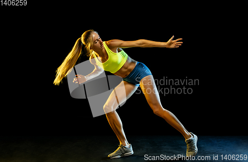 Image of Professional female relay racer training on black studio background in neon light