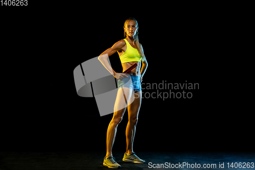 Image of Professional female relay racer training on black studio background in neon light