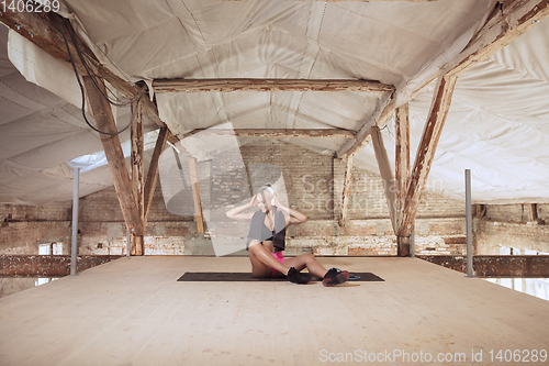 Image of A young athletic woman working out on an abandoned construction site