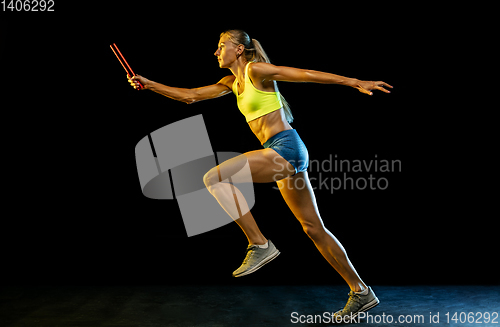 Image of Professional female relay racer training on black studio background in neon light