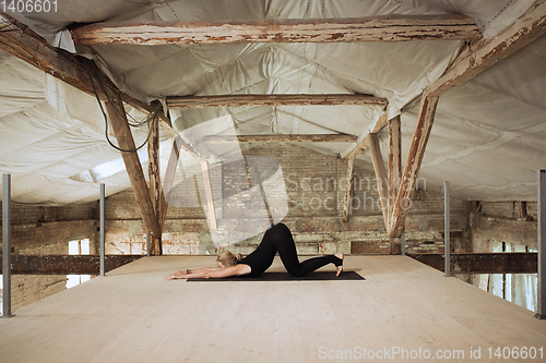 Image of Young woman exercises yoga on an abandoned construction site