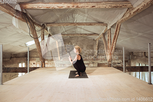 Image of Young woman exercises yoga on an abandoned construction site