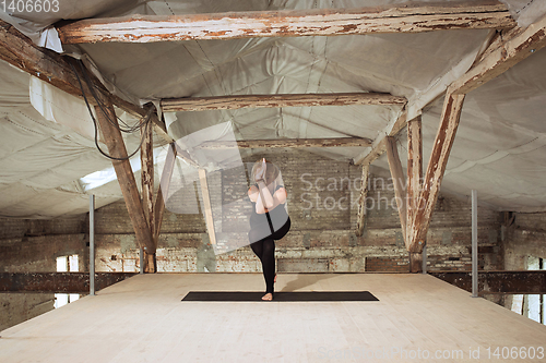 Image of Young woman exercises yoga on an abandoned construction site