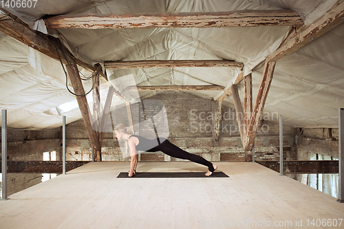 Image of Young woman exercises yoga on an abandoned construction site