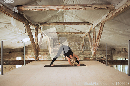 Image of Young woman exercises yoga on an abandoned construction site