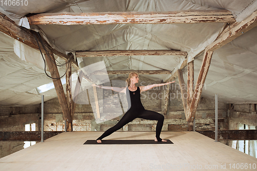 Image of Young woman exercises yoga on an abandoned construction site
