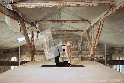 Image of Young woman exercises yoga on an abandoned construction site