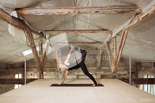 Image of Young woman exercises yoga on an abandoned construction site
