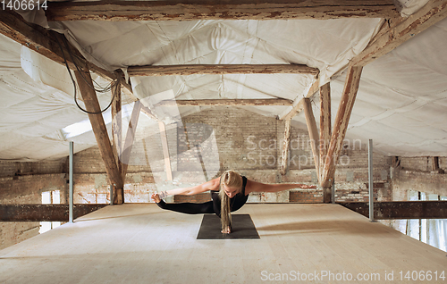 Image of Young woman exercises yoga on an abandoned construction site