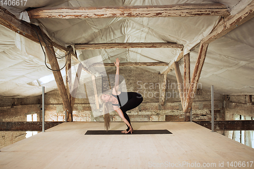 Image of Young woman exercises yoga on an abandoned construction site