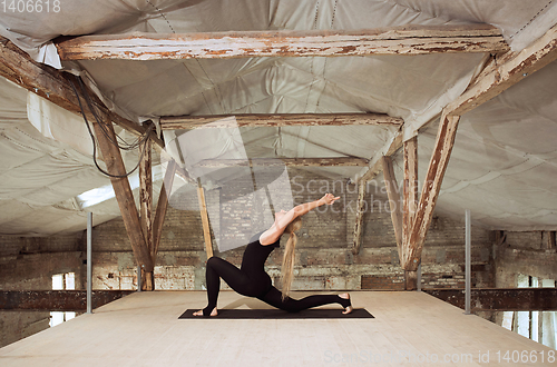 Image of Young woman exercises yoga on an abandoned construction site