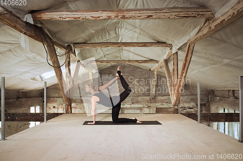 Image of Young woman exercises yoga on an abandoned construction site