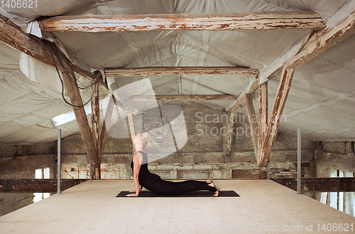 Image of Young woman exercises yoga on an abandoned construction site