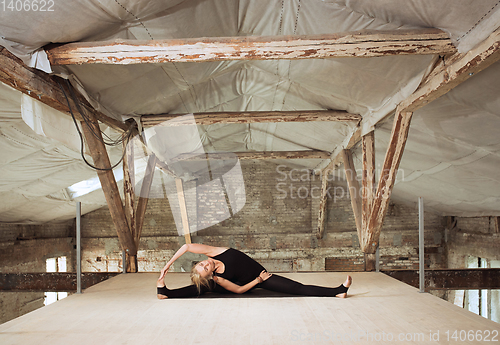 Image of Young woman exercises yoga on an abandoned construction site