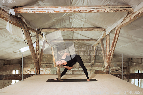 Image of Young woman exercises yoga on an abandoned construction site