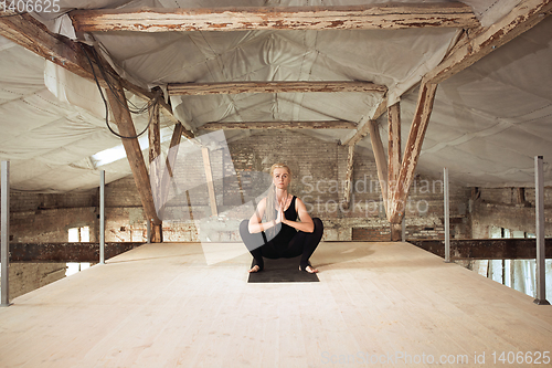 Image of Young woman exercises yoga on an abandoned construction site