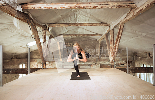 Image of Young woman exercises yoga on an abandoned construction site