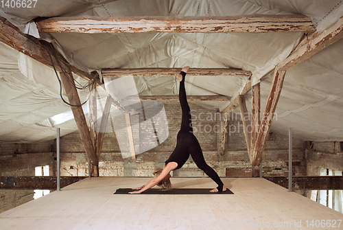 Image of Young woman exercises yoga on an abandoned construction site