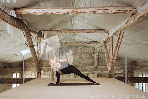 Image of Young woman exercises yoga on an abandoned construction site