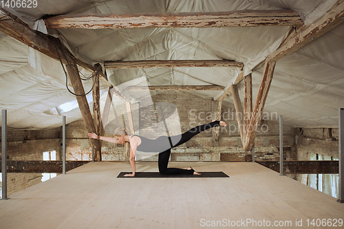 Image of Young woman exercises yoga on an abandoned construction site