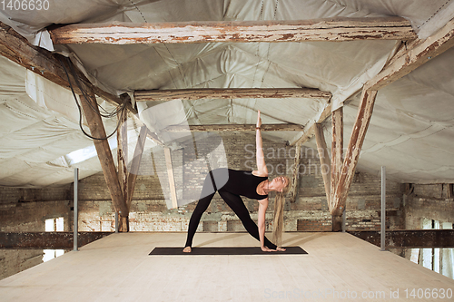 Image of Young woman exercises yoga on an abandoned construction site