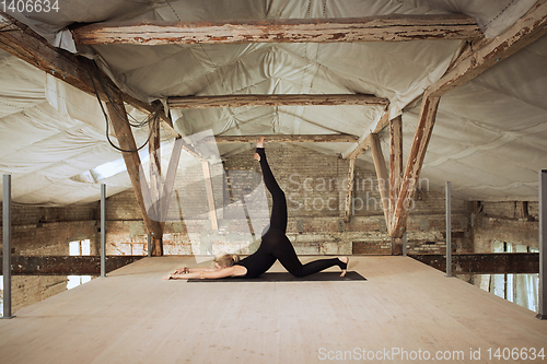 Image of Young woman exercises yoga on an abandoned construction site