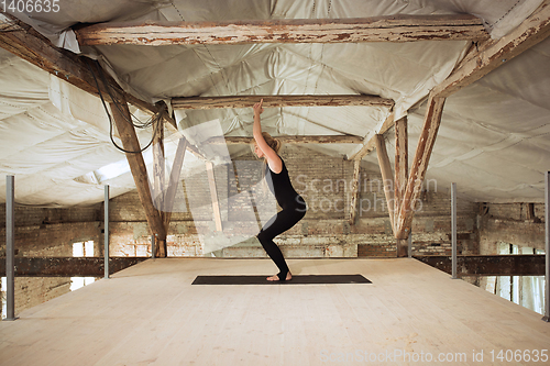 Image of Young woman exercises yoga on an abandoned construction site