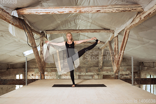 Image of Young woman exercises yoga on an abandoned construction site