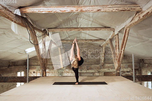Image of Young woman exercises yoga on an abandoned construction site