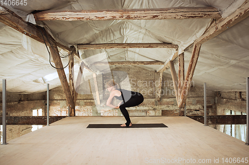 Image of Young woman exercises yoga on an abandoned construction site