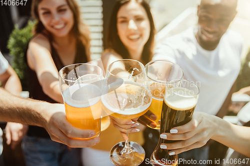 Image of Young group of friends drinking beer and celebrating together