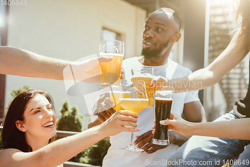 Image of Young group of friends drinking beer and celebrating together